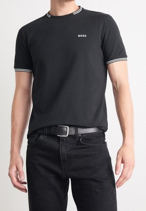 T-shirt noir en coton avec un col rond, une bordure rayée blanche et un petit logo "BOSS" sur la poitrine, associé à un jean noir.