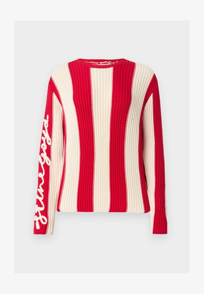 Πλεκτό πουλόβερ με μακριά μανίκια, φαρδιές κάθετες κόκκινες και εκρού ρίγες και λευκό κείμενο με πλάγια γραφή στο αριστερό μανίκι.