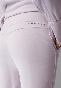 Ljuslavendel sweatpants i mjukt tyg, med en slät textur och fickor, samt en kontrasterande bourgogne "BOGNER"-logotyp på midjebandet.
