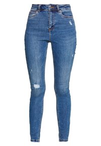 Jean skinny bleu taille haute avec légère usure sur la cuisse et le genou, fermeture frontale à boutons et design à cinq poches.