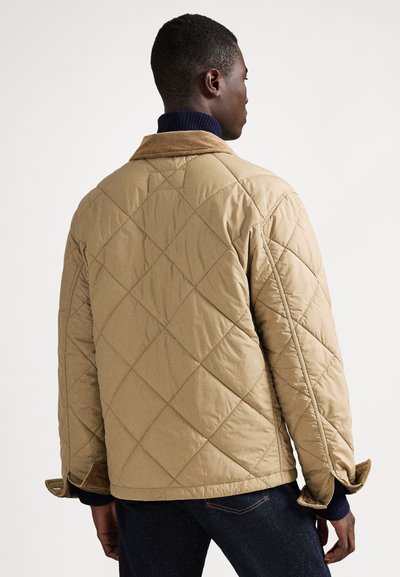 Pikowana brązowa kurtka z kołnierzem z sztruksu i granatowymi ściągaczami, charakteryzująca się luźnym krojem i widocznymi wzorami szwów.