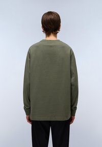 Camicia a maniche lunghe verde oliva, in morbido cotone, vestibilità rilassata, colletto tondo, con orlo dritto e polsini a coste, mostrata da dietro.