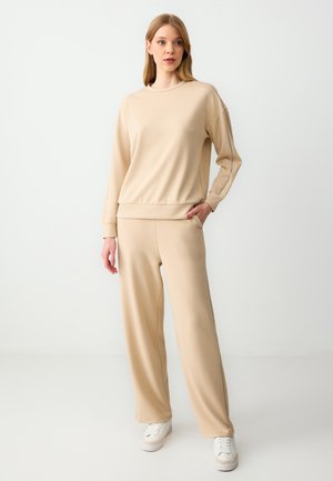 Beige sweatshirt and matching wide-leg pants, made of soft fabric. Features a round neckline, dropped shoulders, and side pockets.