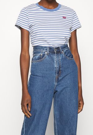 Blue and white striped t-shirt with a round neckline and small red logo. Paired with high-waisted blue denim jeans. Casual fit.