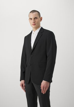 Schwarze Anzugjacke mit zwei vorderen Knöpfen, einer einzelnen Brusttasche und Reverskragen. Getragen über einem weißen Hemd mit Button-Down-Kragen.