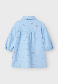 Camicia azzurra chiara con colletto e maniche a sbuffo. Presenta piccole ricami di farfalle argento in tutto il tessuto. La stoffa appare liscia e leggera.