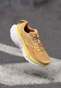 Baskets de course légères jaunes avec une tige en mesh, un design texturé, un système de laçage minimal, une semelle rembourrée et des accents de branding subtils.