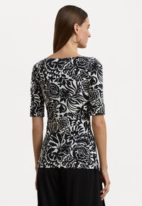 Top a fiori in bianco e nero con maniche corte, scollatura tonda e silhouette aderente, realizzato in un tessuto morbido.