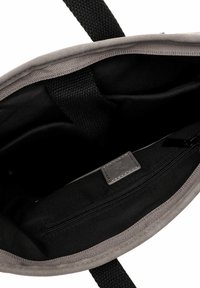 Pilkos audinės pirkinių maišas su juodu interjeru. Yra užtrauktuko kišenė ir tekstūruotos rankenos. Išklotas švelnia medžiaga.