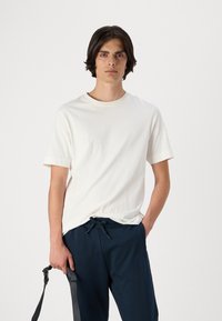 Hvid bomulds t-shirt med korte ærmer, rund halsudskæring og en afslappet pasform, parret med marineblå sweatpants med snor i taljen.