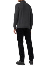 Szary sweter z dzianiny z kołnierzem, widziany od tyłu, zestawiony z czarnymi spodniami sztruksowymi i czarnym obuwiem. Gładka faktura.