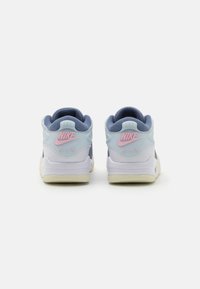 Nike Air sneakeri ar gaiši zilām augšdaļām, tumši zilām akcentiem un rozā zīmola logotipu. Dizains ietver mīkstinātu papēdi un strukturētu zoli.