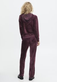 Bordeaux velours hoodie en broeken set met een relaxed fit, met een capuchon en een gladde textuur, gecombineerd met zwarte chunky laarzen.