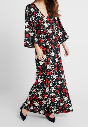 Lang, sort blomsterkjole med røde og hvide blomster; struktureret stof; V-udskæring; brede klokkeærmer; indsnævret talje; svajende silhuet.