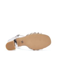 Sandal con tacco trasparente, con una soletta beige e suola in gomma testurizzata. Presenta dettagli metallici e più cinturini diagonali.