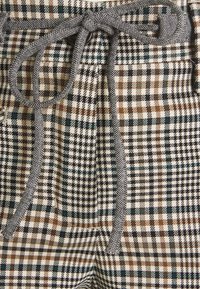 Plaid pants featuring a mix of brown, black, and teal squares with a textured fabric; includes a gray fabric tie at the waist.