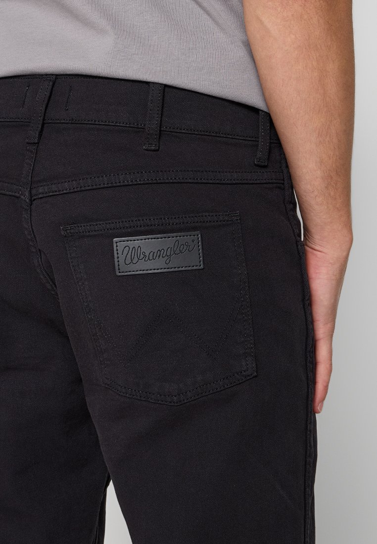 Schwarze Denim-Jeans mit einem Lederpatch mit dem "Wrangler"-Logo auf der Gesäßtasche, gerader Schnitt mit dezenten Steppnähten.