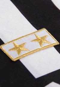 Zwart-wit gestreepte stof met een witte patch waarop twee gouden geborduurde sterren staan, omlijnd met gouden draad.