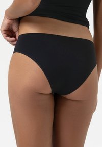 Zwarte bikinibroek met een gladde textuur en minimale bedekking, met duidelijke lijnen en een hoge uitsnede voor een strakke uitstraling.
