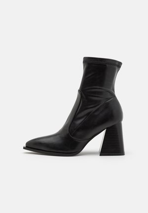 Bottines noires en cuir lisse, avec un bout pointu, un contrefort de cheville élastique et un talon empilé texturé.