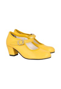 Zapatos Mary Jane amarillos con tacones bajos de bloque y correas con hebilla plateada sobre un fondo blanco.