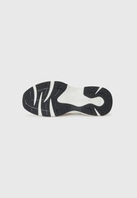 Schuhsohle mit einem schwarzen Gummilaufmuster, das Rillen für Traktion sowie eine weiße Zwischensohle für Dämpfung aufweist. Sauberes, minimales Design.