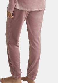 Zachte roze fleece joggingbroek met een relaxte pasvorm, elastische enkelmanchetten en zijnaad. Het materiaal heeft een gladde, comfortabele textuur.