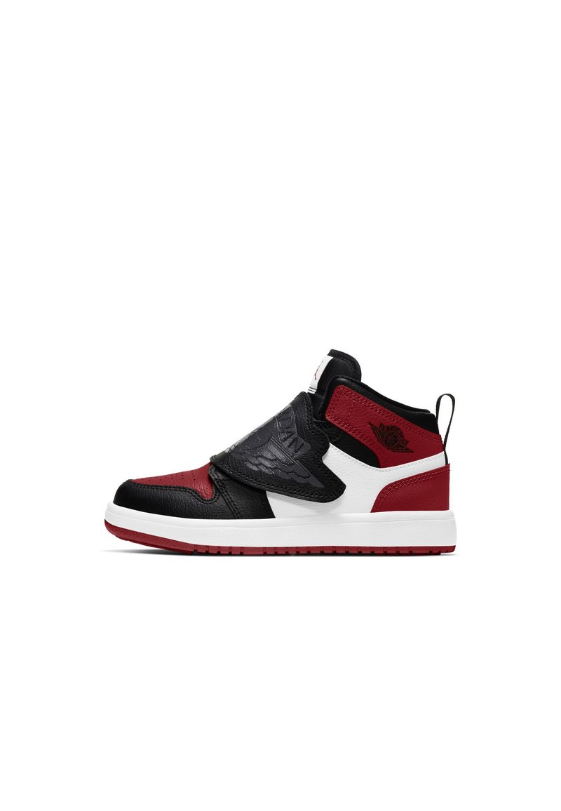 Zapatilla alta en cuero negro, rojo y blanco; cuenta con una correa de velcro, detalles texturizados y una suela de goma blanca con un logo.