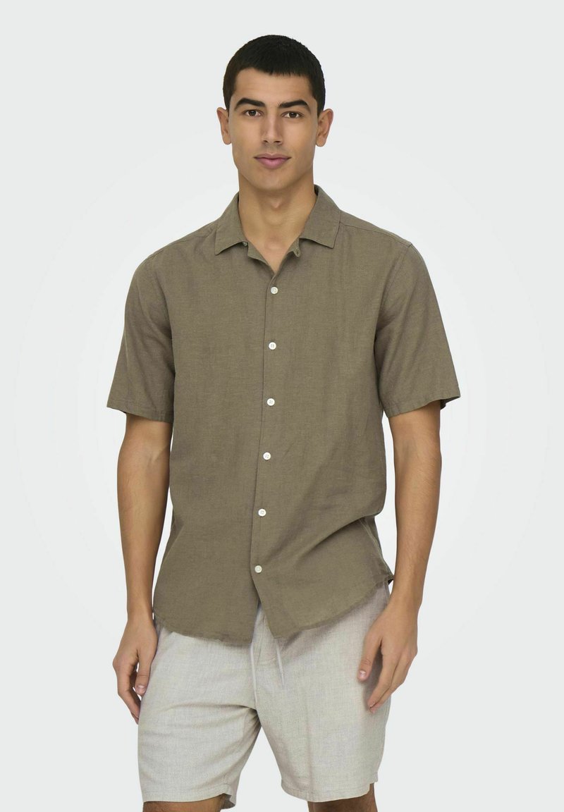 Kortærmet, brun linned skjorte med knap-frontdesign. Har en afslappet pasform og en klassisk krave, parret med lyse shorts.