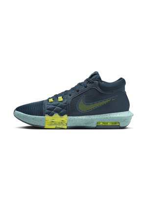 Scarpa da basket Nike blu scuro con dettagli gialli, texture trapuntata vicino alle stringhe e suola azzurro chiaro con macchie e ammortizzazione ad aria visibile.