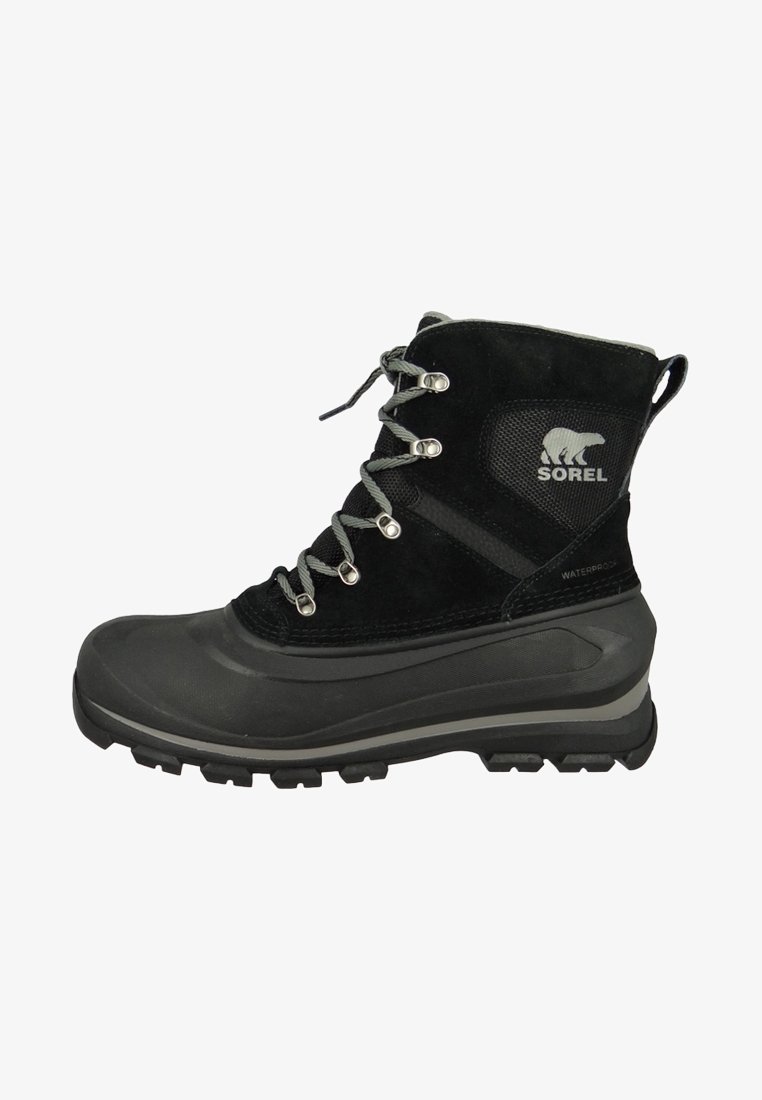Botte d'hiver noire imperméable avec semelle à gros crampons, lacets gris, œillets en métal et logo Sorel représentant un ours polaire sur la cheville.