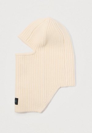 Μπεζ πλεκτή μπαλακλάβα με ραβδωτή υφή, σχεδίαση πλήρους κάλυψης και εσοχές στο πλάι για το πρόσωπο. Διαθέτει μια μικρή μαύρη ετικέτα στο τελείωμα.