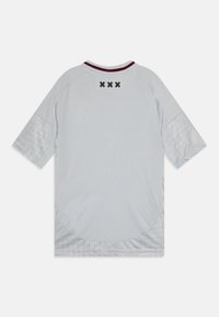 Vaaleanharmaa t-paita, jossa on lyhyet hihat, pyöreä kaula-aukko, viininpunaiset yksityiskohdat kaula-aukolla ja geometrinen kuvio alasivuilla. Takana neljä mustaa pistettä.