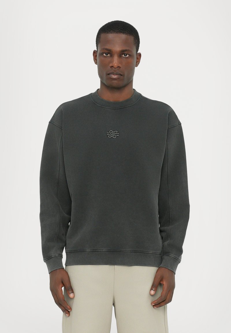 Mørkegrå sweatshirt med rund hals og ribbede manchetter. Har et tekstureret grafisk logo på brystet. Blødt stof.