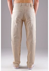 Beige Baumwollhosen mit geraden Beinen, sichtbaren Gesäßtaschen und einem gesteppten Bund. Verfügt über eine subtile Textur und Kontrastnähte.