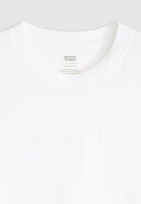 Fehér pamut póló, kerek nyakkivágással és domború "Levi Strauss & Co." logóval elöl, belül vintage fit címkével.