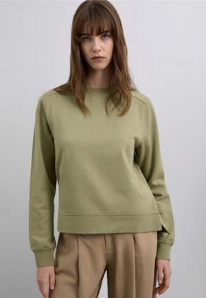 Sudadera de color verde claro hecha de material suave, con cuello redondo acanalado, mangas largas y un ajuste relajado. Pequeño detalle de logo en la parte delantera.