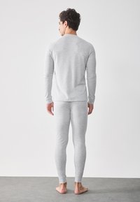 Ljusgrå långärmad topp och matchande leggings, tillverkade av mjukt tyg, figurnära design med ribbad muddar, sömlig baksida, inga synliga mönster eller dekorationer.