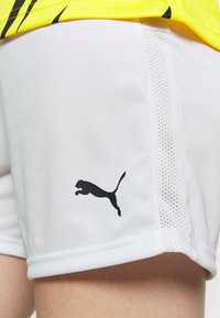 Weiße Shorts mit einem schwarzen Puma-Logo. Hergestellt aus glattem Stoff mit Netz-Seitenpanelen, die ein sauberes, sportliches Design präsentieren.