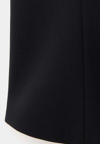 Gros plan sur un tissu noir lisse avec une couture visible courant verticalement près du bord droit.