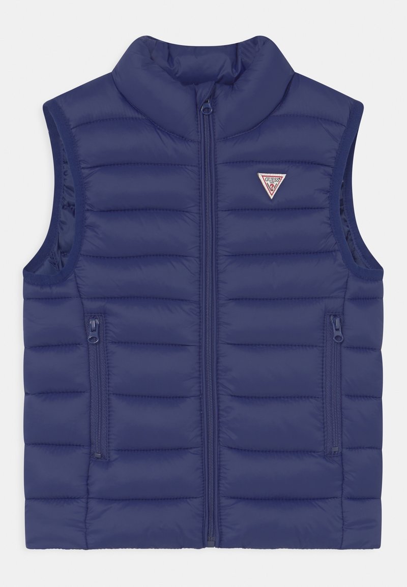 Veste sans manches matelassée bleu marine avec fermeture éclair à l'avant, deux poches latérales zippées et un petit logo triangulaire sur la poitrine.