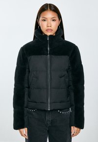 Černá zimní bunda s měkkým fleecovým límcem a rukávy, zipovým uzávěrem a prošívaným designem se bočními kapsami.
