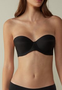 Svart bandeau-bh i slät tyg, med en formad kupa och sömlös finish. Inkluderar underwire-stöd och sidoboning.