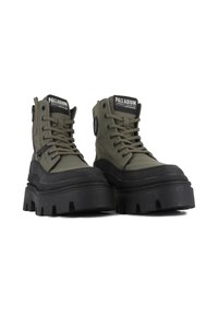 Bottes de combat en toile verte avec une semelle en caoutchouc noir épaisse, bout rond et design à lacets, présentant une fermeture éclair sur le côté et un patch logo.