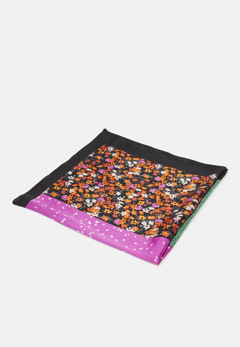 Foulard en soie avec bordure noire, motif floral en orange, blanc et violet, et une section violette à pois blancs, plié sur fond blanc.