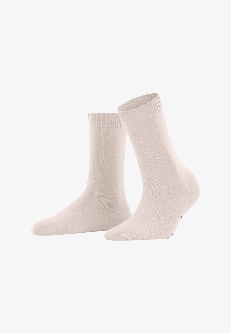 Un paio di calzini crew semplici color beige chiaro con bordi a coste esposti su uno sfondo bianco.