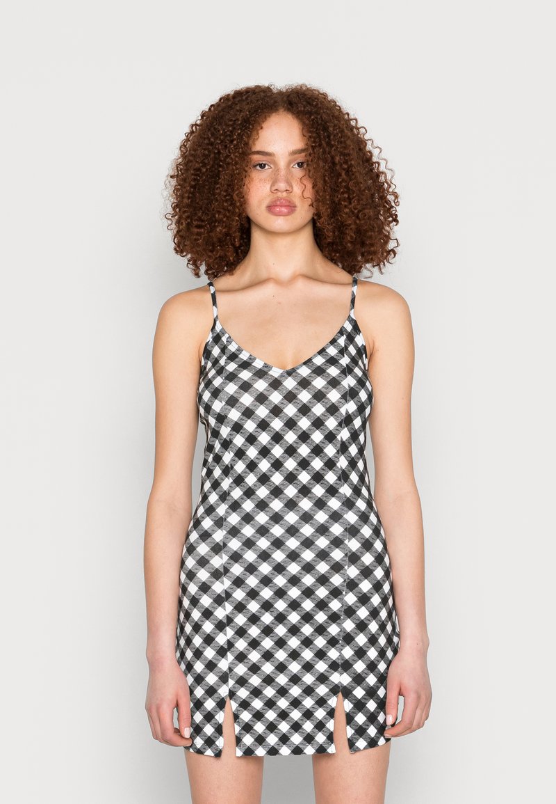 Vestido preto e branco em padrão xadrez com alças finas ajustáveis, decote em V e fendas laterais, feito de um tecido suave.