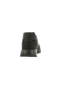 Svart idrottssko med en slät yta, vadderad häl och hållbar gummiyttersula. Logotypdetalj synlig på hälen.