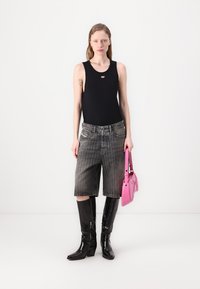 Svart tank topp, grå denimshorts og knelang svarte støvler. Rosa håndveske med et elegant design. Bakgrunnen er helt hvit.