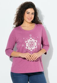 Lavendelfarbenes Longsleeve-T-Shirt mit rundem Halsausschnitt, ausgestattet mit einem weißen astrologischen Grafikdesign in der Mitte und aus weichem, leichtem Stoff.